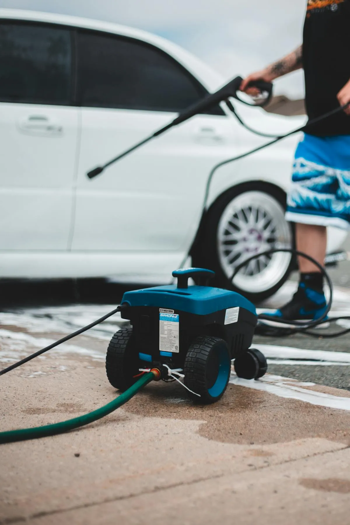 Person pressure washing a driveway with a residential pressure washer