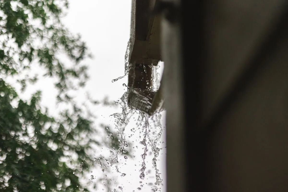Worker safely cleaning gutters using proper ladder setup and stabilization